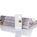 Stapel Zeitungen mit E-Paper Smartphone